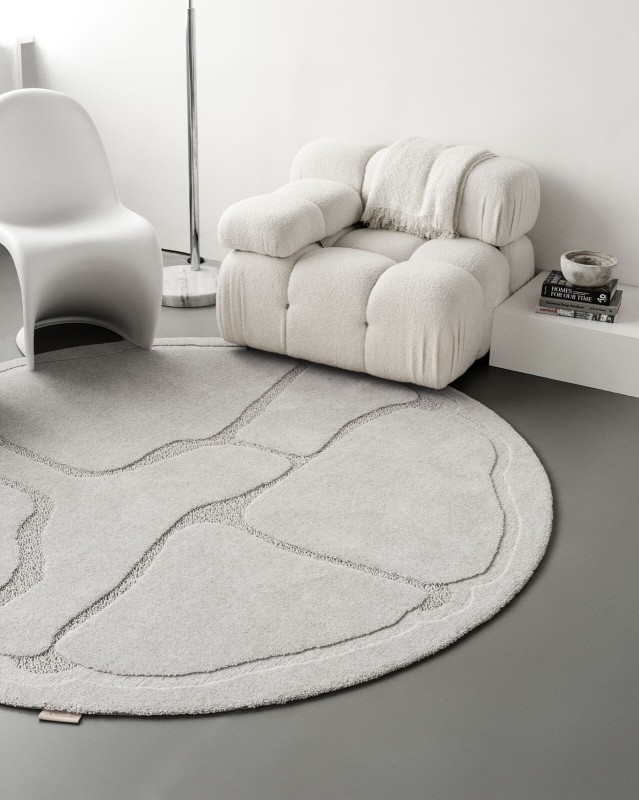 Okrągły dywan wełniany jasnoszary Agnella Ladnini Morphic Organica w pokoju