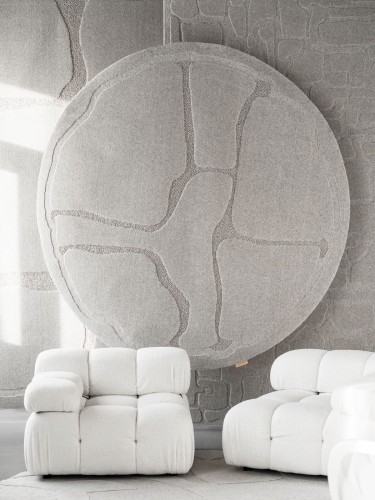 Okrągły dywan wełniany jasnoszary Agnella Ladnini Morphic Organica na ścianie