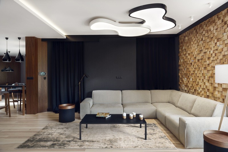 Dywan wełniany loftowy Agnella Isfahan M Contre popielaty w nowoczesnym salonie z jasną kanapą na tle grafitowej ściany i granatowych zasłon