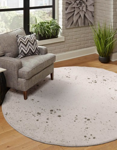 Dywan okrągły wełniany Agnella Isfahan M Sean kolor alabastrowy na podłodze na tle szarego fotela