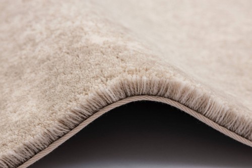 Detal zakończenia typu binding dywanu Agnella Calisia Bran biały w pokoju dziennym