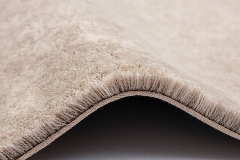 Detal zakończenia typu binding dywanu Agnella Calisia Bran biały w pokoju dziennym