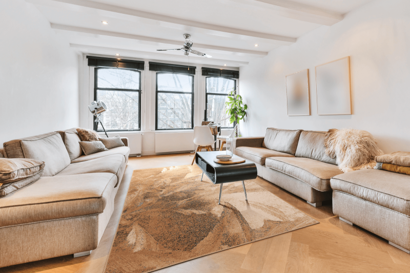 Dywan wełniany Agnella Isfahan Lotis kolor beżowy w nowoczesnym salonie z dużymi kanapami i oknem