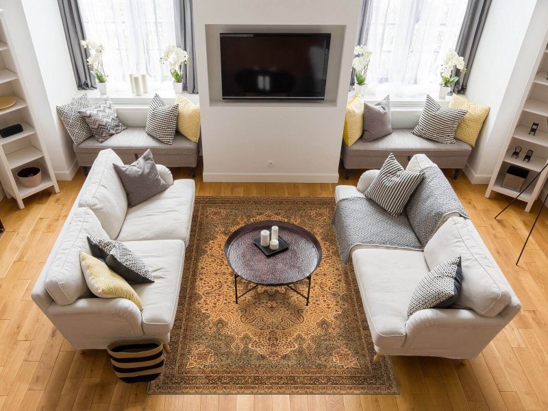 Dywan wełniany Agnella Agnus Namak kolor oliwka w przytulnym salonie z szarymi kanapami i kominkiem