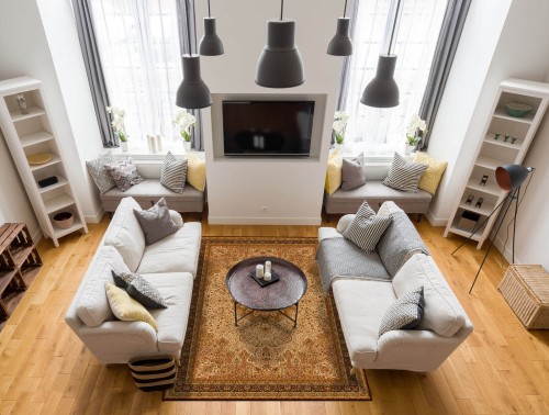 Dywan wełniany Agnella Agnus Namak w kolorze sahara w salonie na tle jasnych kanap i kominka