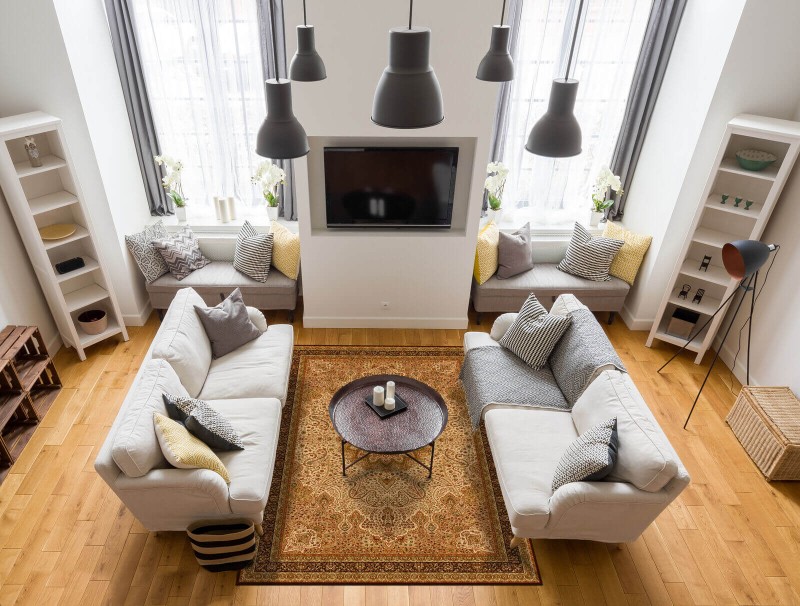 Dywan wełniany Agnella Agnus Namak w kolorze sahara w salonie na tle jasnych kanap i kominka