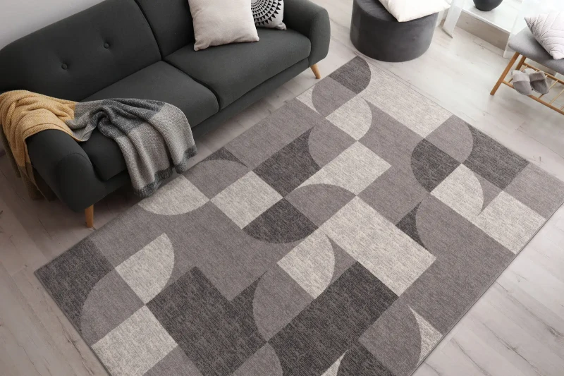 Dywan wełniany art deco Agnella Ballata Gavina kolor szary w salonie z grafitową kanapą