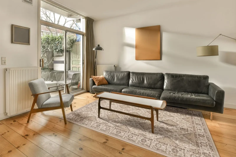 Dywan wełniany Agnella Ballata Emivo w kolorze beżowym w salonie nowoczesnym w grafitową kanapą