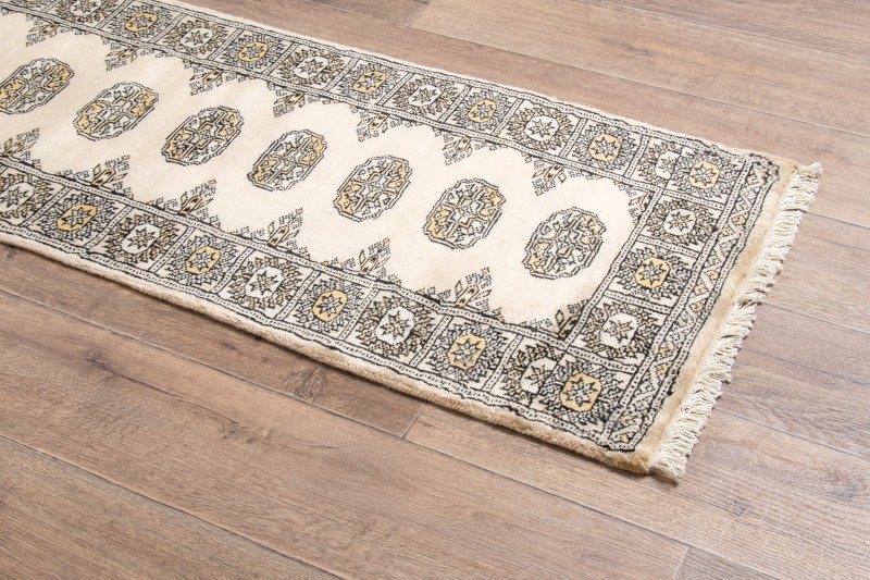 Na podłodze dywan orientalny pakistański Bukhara 63x181 cm