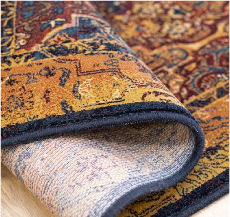 Fragment zwiniętego dywanu z widocznym obszyciem i spodem dywanu Dywilan Superior Kain miedź