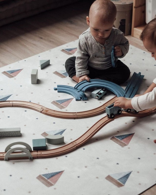Małe dziecko i drewniane tory kolejowe na macie Little Sailor