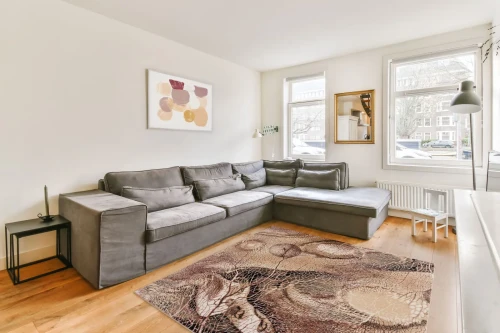 Dywan wełniany kwadratowy Agnella Isfahan Bellona ciemno beżowy w salonie nowoczesnym w grafitową kanapą