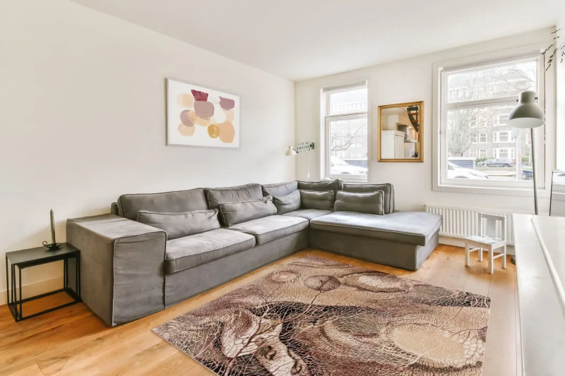 Dywan wełniany kwadratowy Agnella Isfahan Bellona ciemno beżowy w salonie nowoczesnym w grafitową kanapą