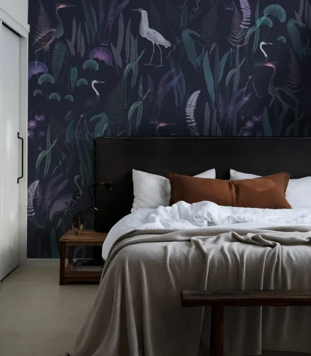 Tapeta Calm Heron Purple na ścianie za łóżkiem w sypialni.webp