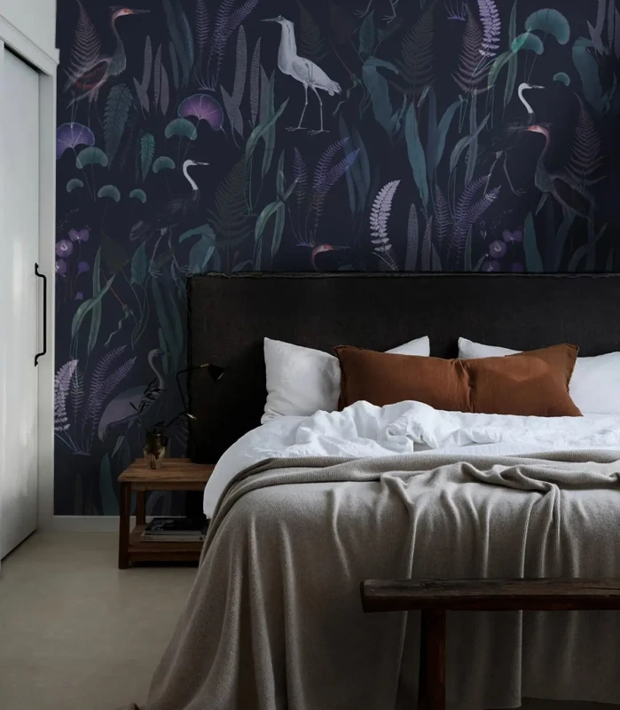 Tapeta Calm Heron Purple na ścianie za łóżkiem w sypialni.webp