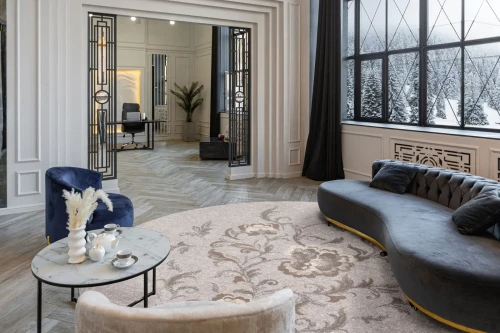 Dywan okrągły wełniany Agnella Ballata Jira kolor szary w salonie urządzonym w stylu glamour z granatową sofą i fotelem