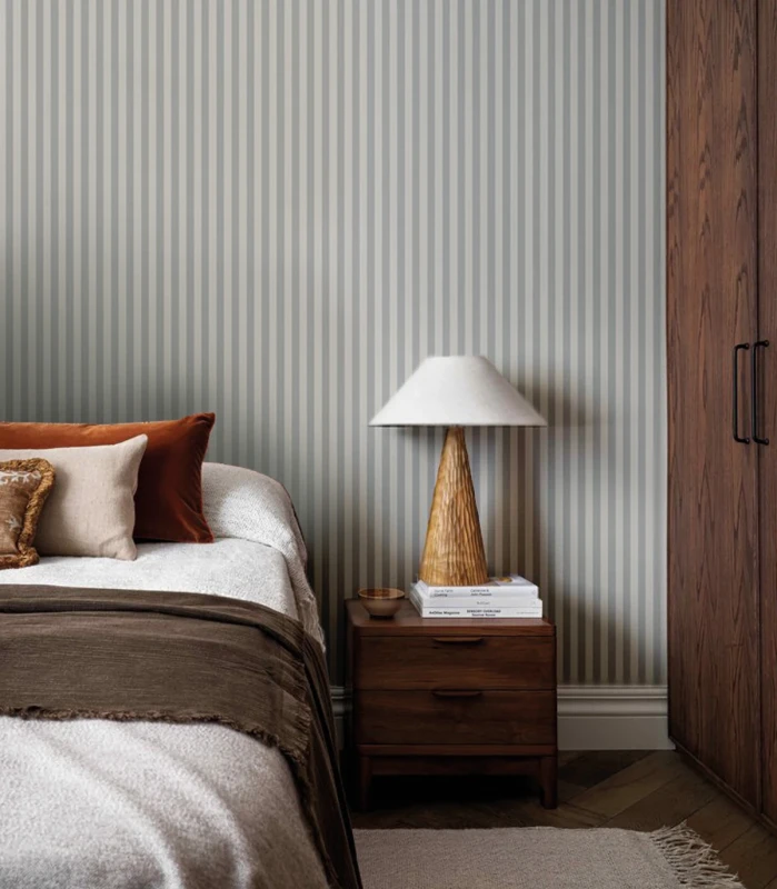 Łóżko i ciemne drewniane meble w sypialni z tapetą Stripe Tranquil Blue.webp