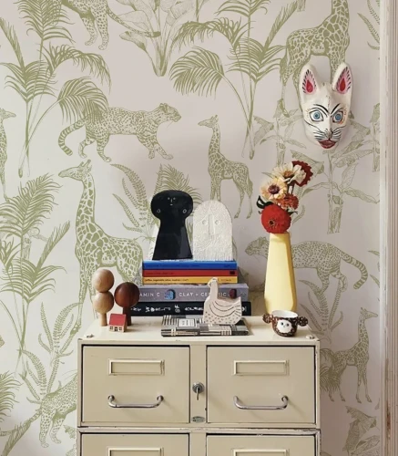 Komoda przy ścianie z tapetą Safari Green z zielonymi dzikimi zwierzętami.webp