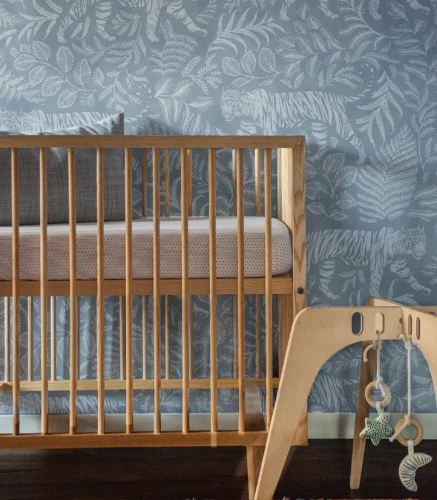 Drewniane dziecięce łóżeczko i zabawka na tle tapety Camouflaged Tiger Blue.webp