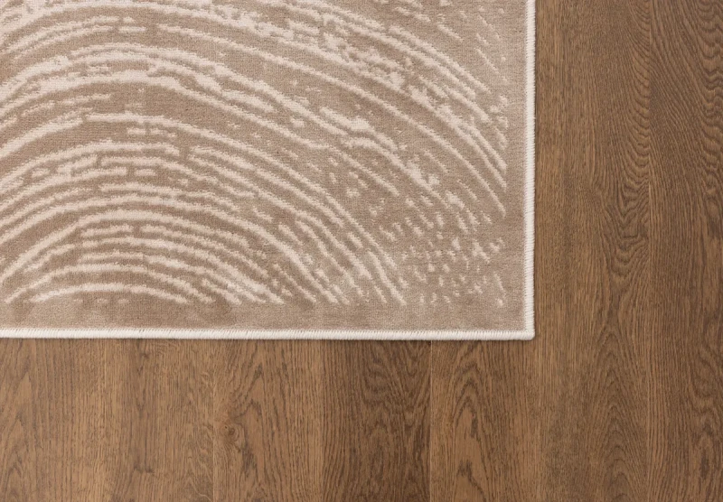 Na ciemnej podłodze fragment dywanu art deco FD Sensi Branco ciemny beż