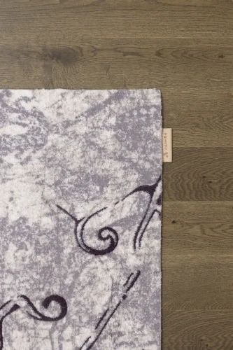 Na ciemnej podłodze róg dywanu wełnianego Agnella Opal Tomas beżowy (binding)